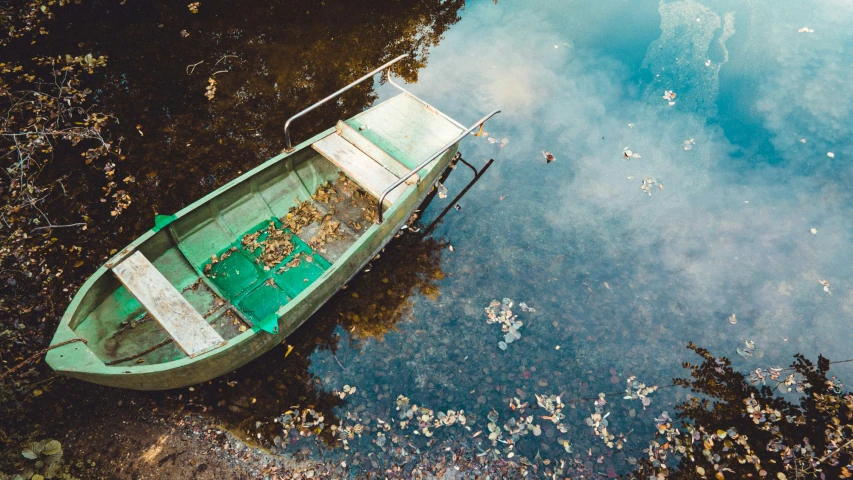 a green and white boat sitting in a body of water