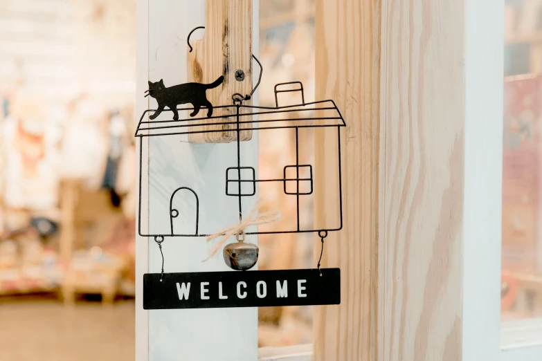 cat on house welcome sign attached to a wooden door handle