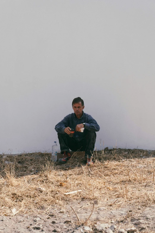 a man is holding a frisbee in his hand while sitting on the sand