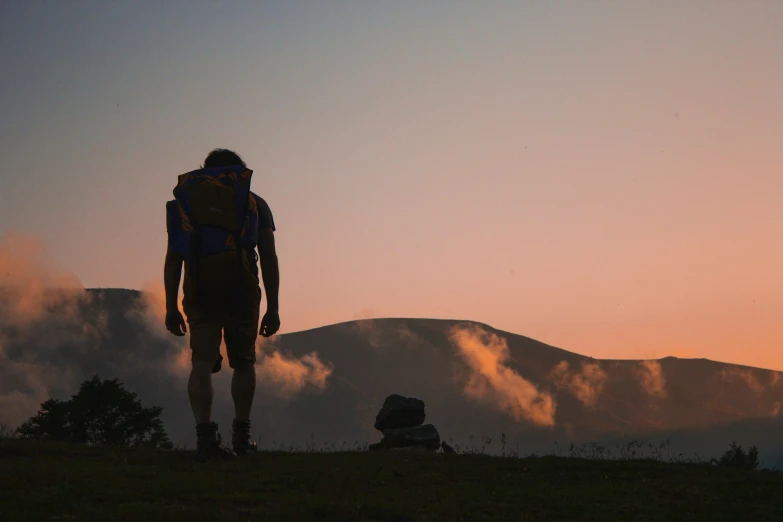 a man with backpack standing on top of a hill