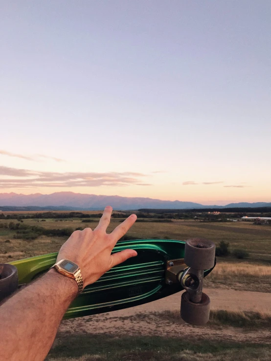 a hand holding a green hose in the middle of a field