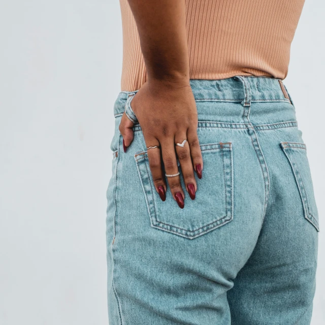 woman in blue jeans holding onto the back end of her pocket
