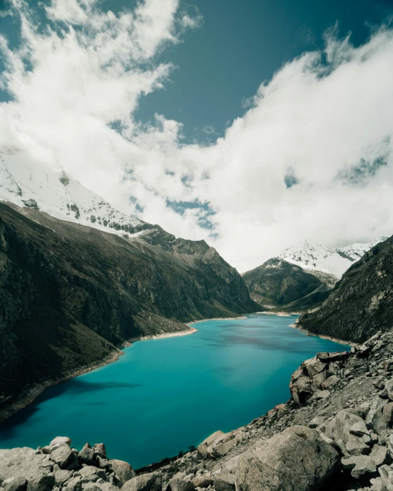 mountain range with lake in foreground, large mountains and cloudy sky