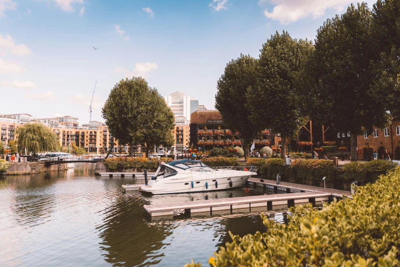 a river scene with a boat tied up on a dock and buildings around