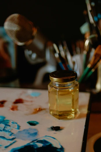 a jar of honey is next to an assortment of paint