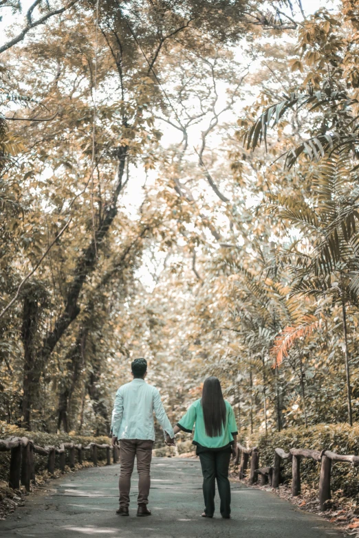 the couple is walking in the forest holding hands