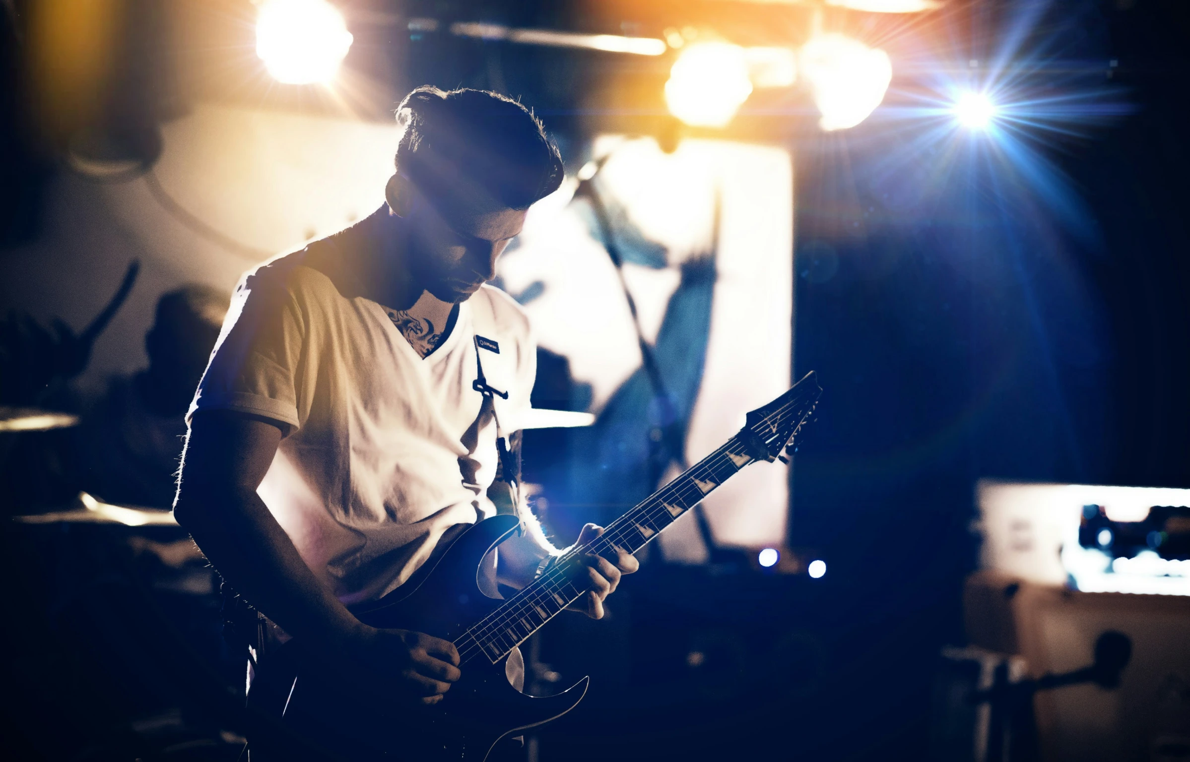 man playing on a guitar while lighting a mic