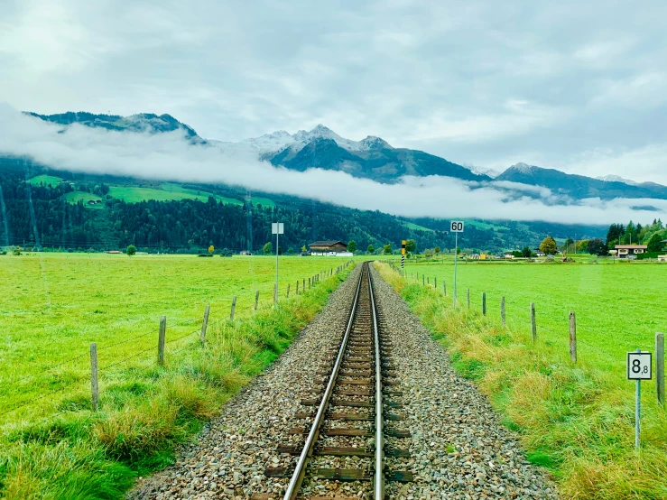 a train track going down a grass covered country side