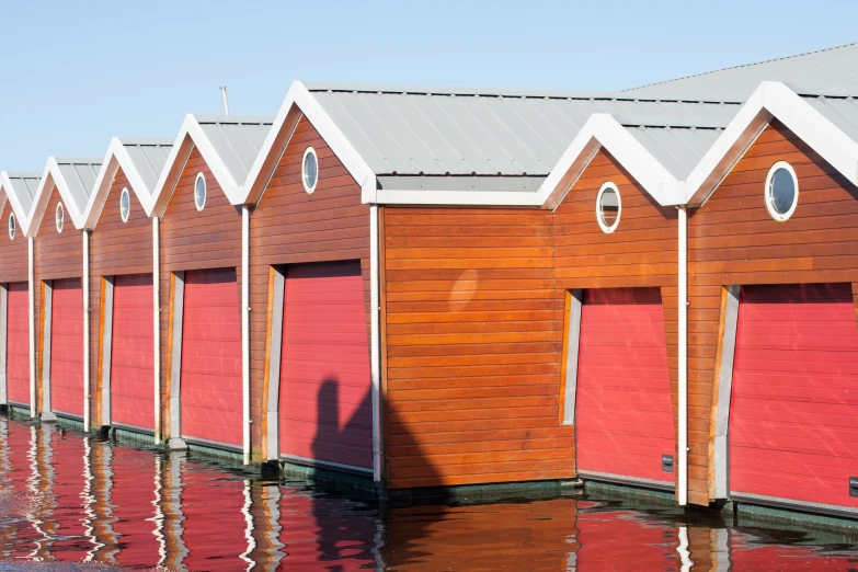 multiple red and brown cabins sitting on a body of water