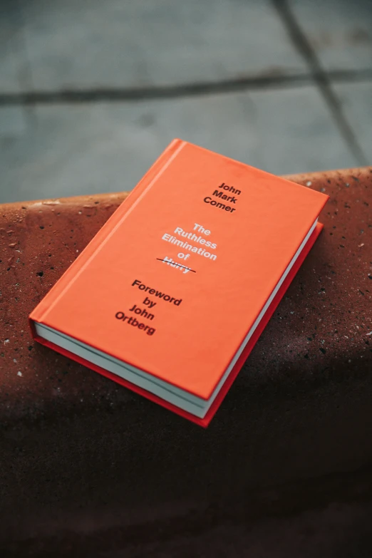 two orange books are stacked together on a brick wall