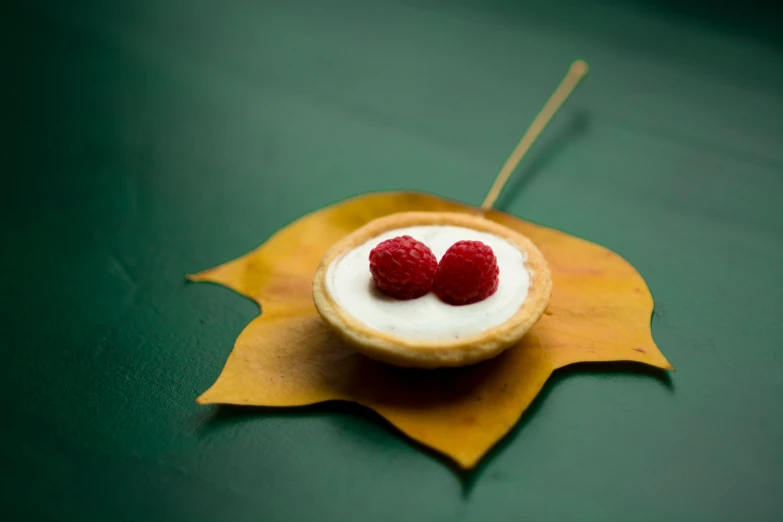 two strawberries in a small leaf on a table