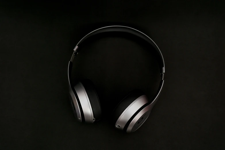 close up of two headphones with black covers on a dark background