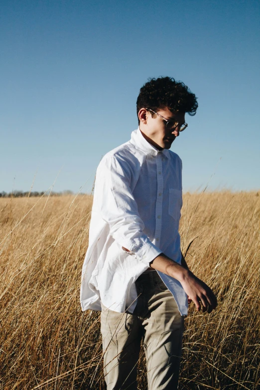 young man standing in large dry grassy field