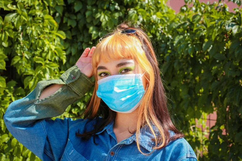 a woman wearing a surgical face mask posing with her hand on her head