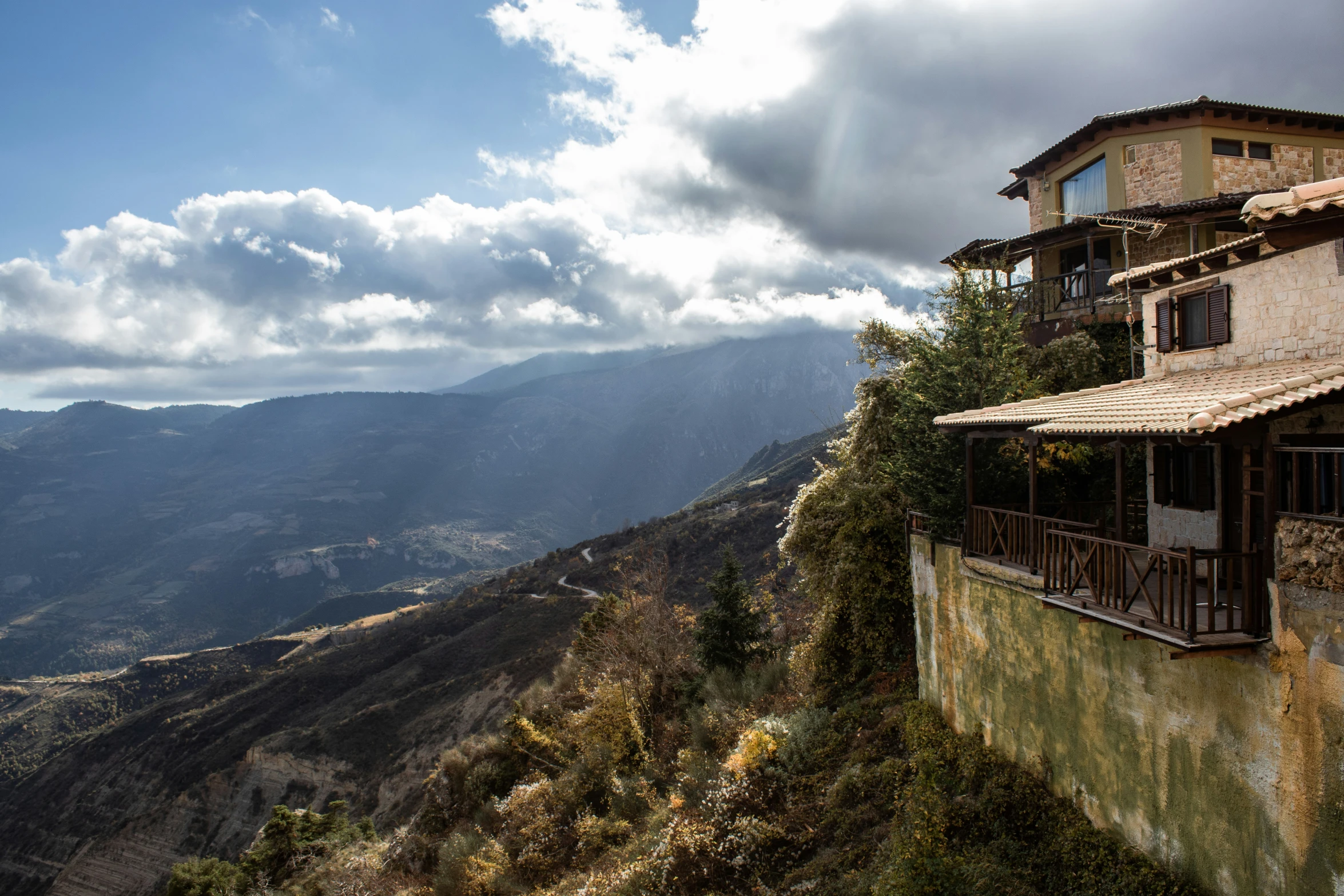 a building sits on the edge of a large cliff, overlooking mountains