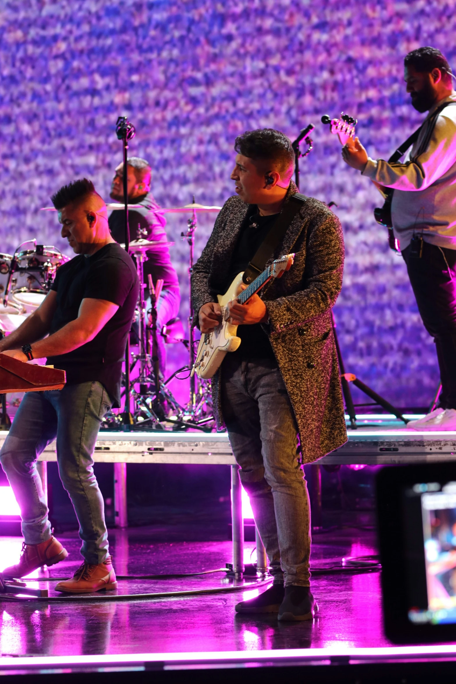 a band playing on stage with a crowd behind