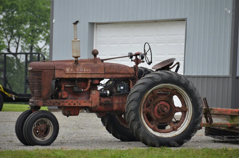 an old farm tractor parked in front of a barn