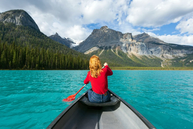 woman paddles her canoe in the middle of turquoise water