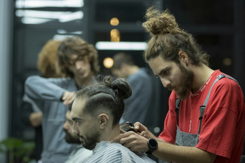 a man getting his hair cut while standing next to a friend