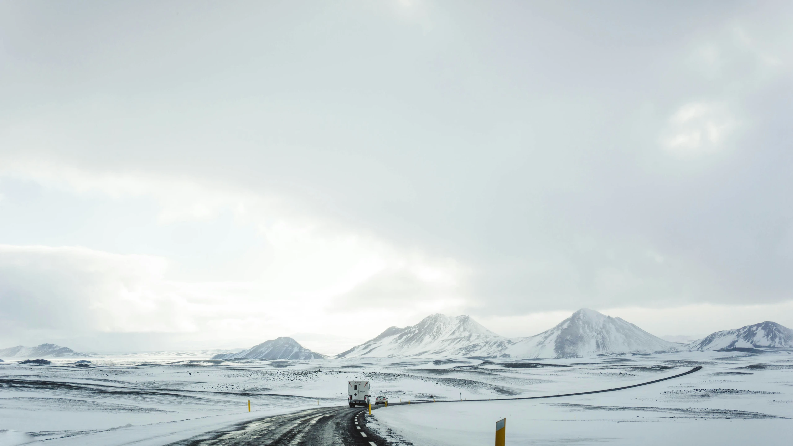 a road going over a hill near a snow covered landscape