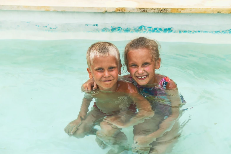 two little children are playing in the pool