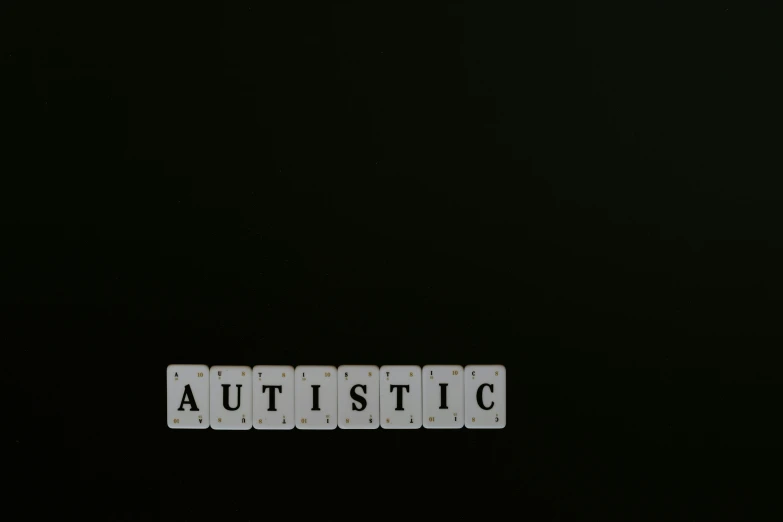 the word autistic written on wooden blocks over a black background