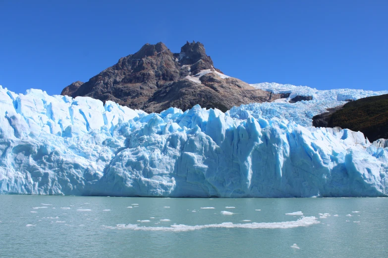 an iceberg is shown on the water near a mountain