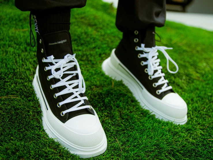 a man's legs and shoes with white laces on them