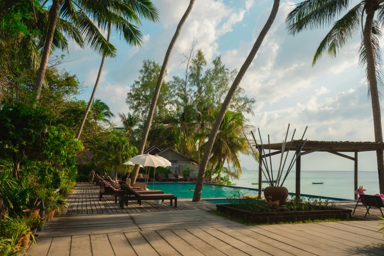 a pool surrounded by palm trees with a gazebo and patio furniture