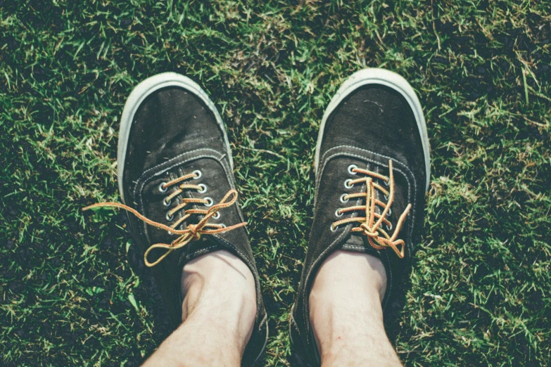 person in grey tennis shoes standing on grass