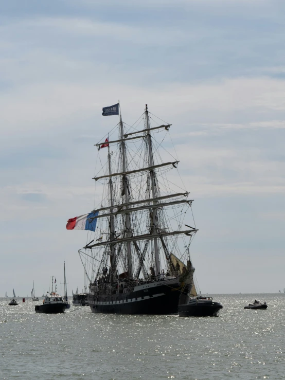 three ships are in the water together under some clouds