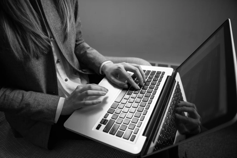 person on a laptop typing while holding another person's hands