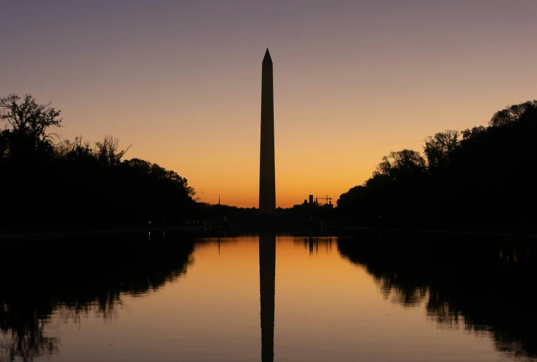 a large monument is next to some water at sunset