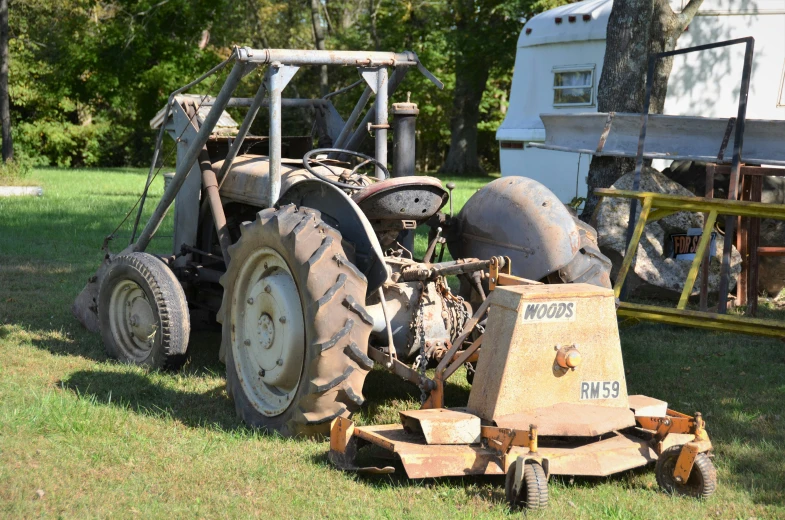 an old tractor sits beside a trailer in the grass