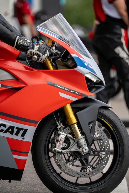 a red motorcycle is parked with some people behind it