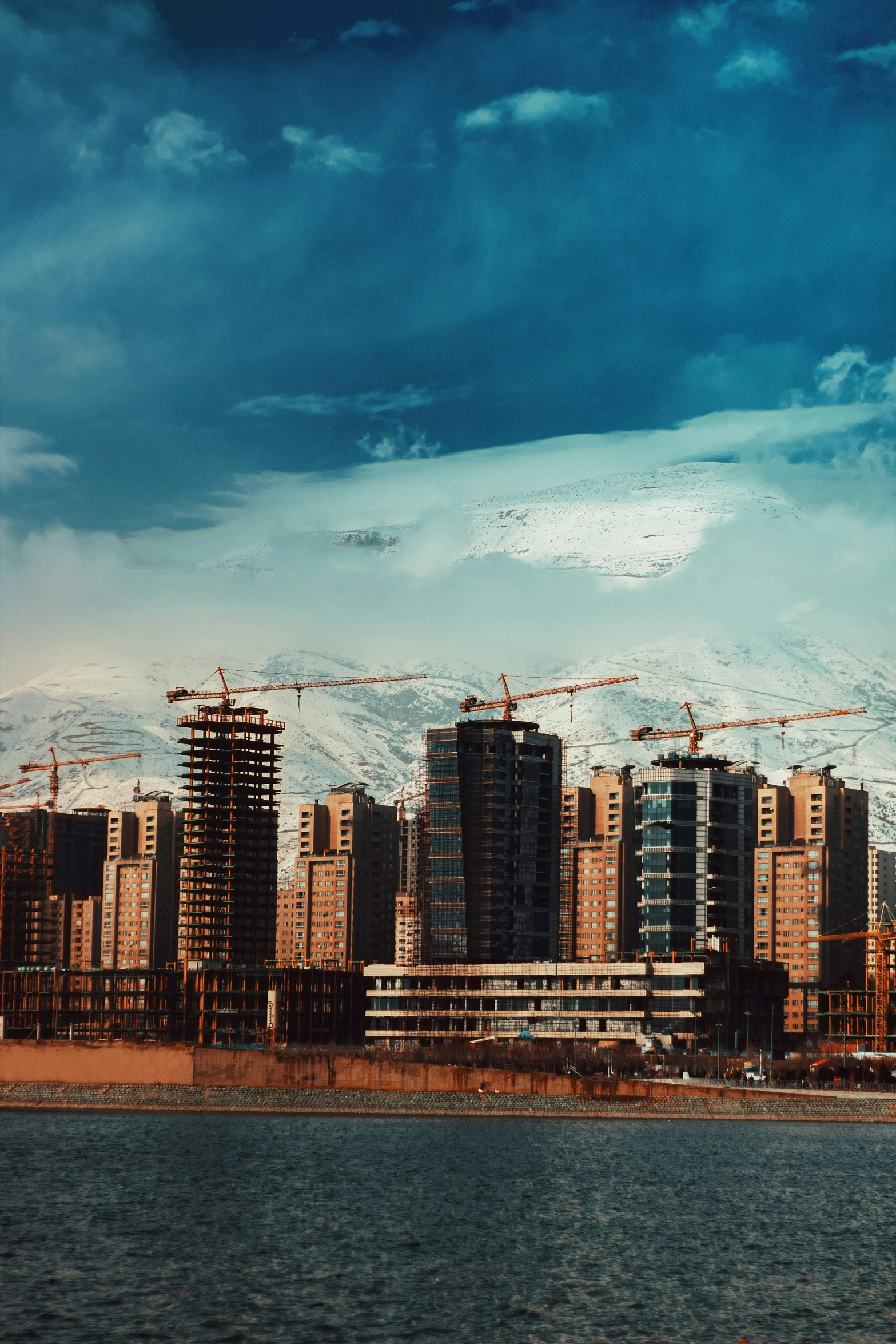 construction cranes in the air over a body of water