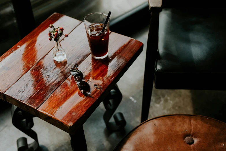 a table with glasses of beverage and some remote controls