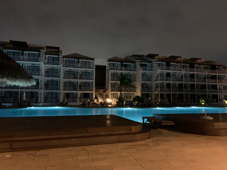 a night time po of a pool with some buildings in the background