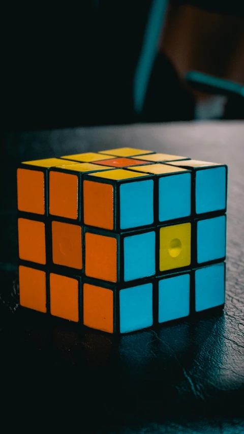 a rubik puzzle sits on a table in the dark