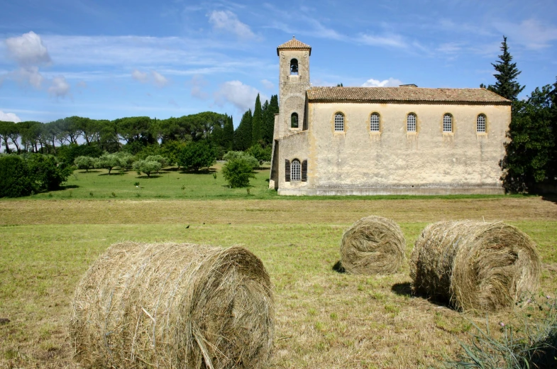 two hay bales in front of an old stone church