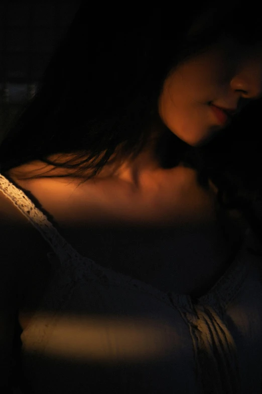 a woman sitting in the dark holding a cell phone