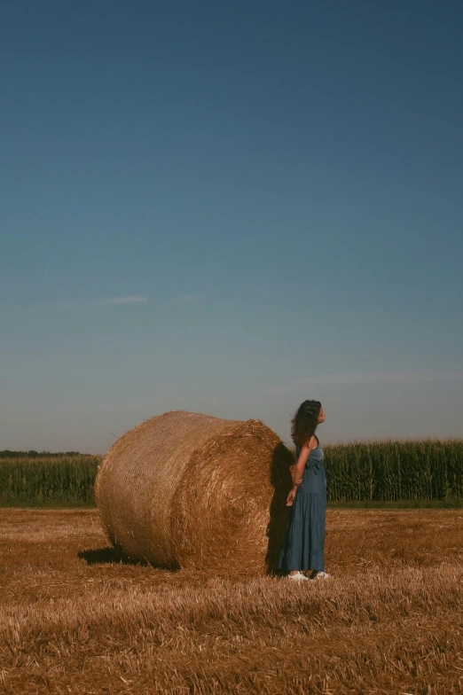 there is a woman standing next to the huge hay bail