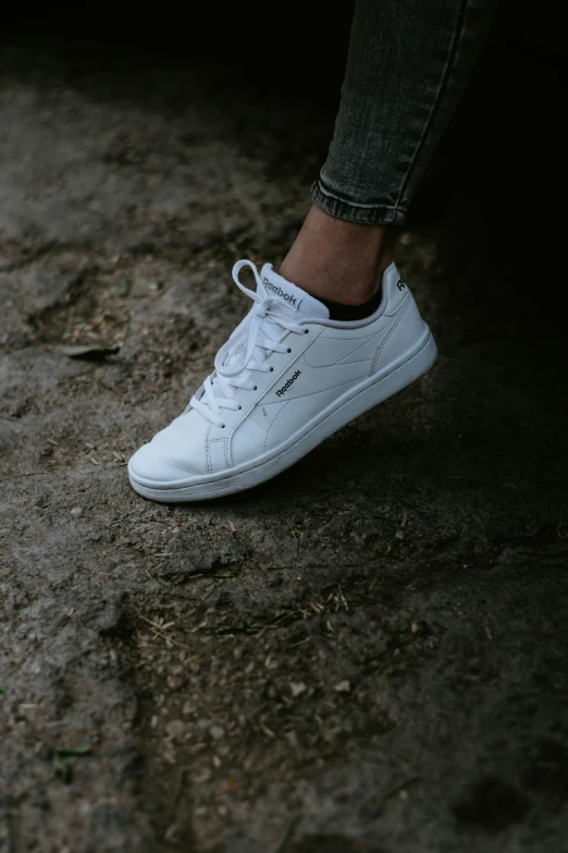 a woman is wearing white tennis shoes and jeans