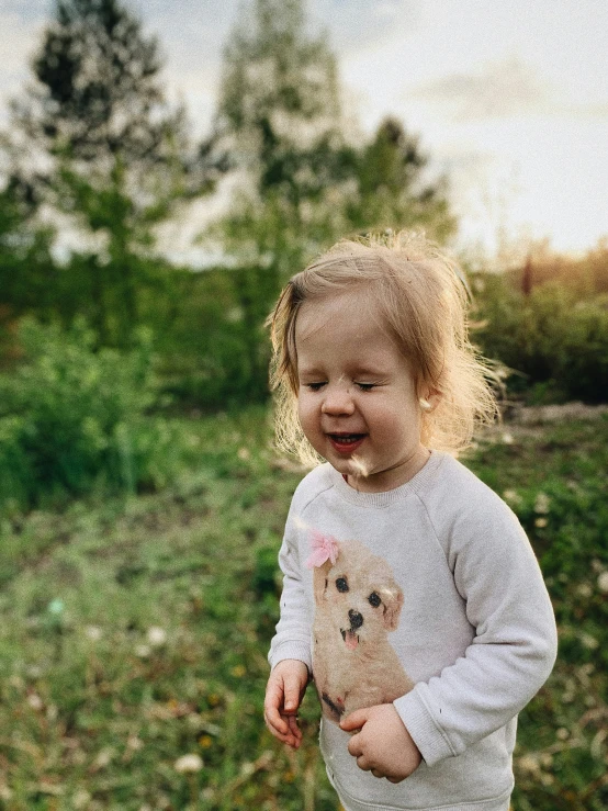 a toddler holding a stuffed bear in a field