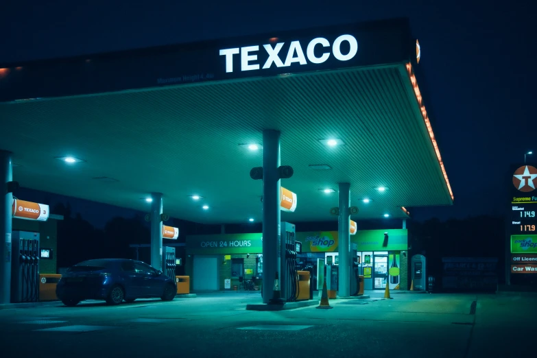gas station at night with lit up cars and gas pumps