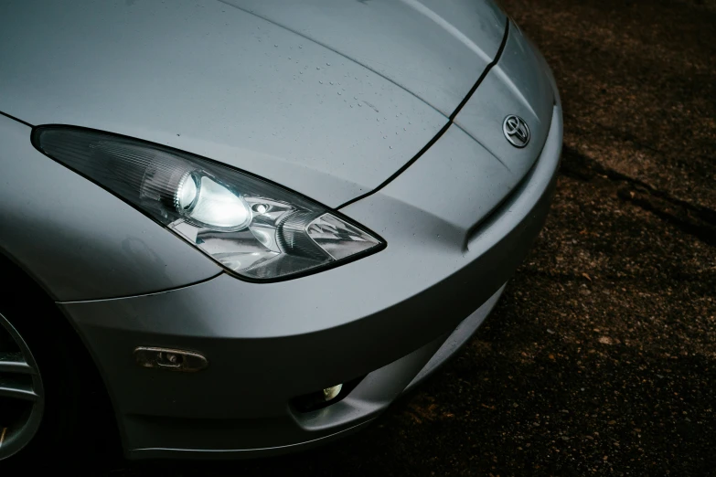 a silver car with its headlight on parked