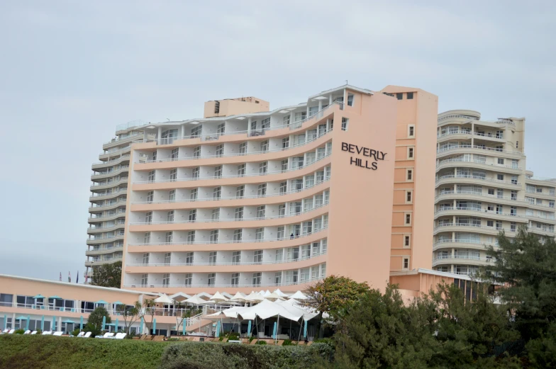 a large building sits behind some trees and bushes