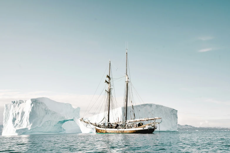 an iceberg floats close to the coast line as it floats near a ship