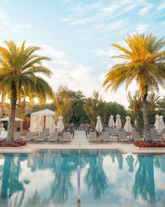 many lounge chairs and umbrellas around an empty pool