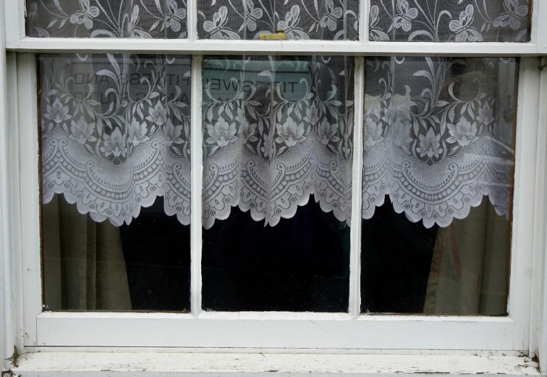 close up of white lace curtains in front of a window